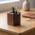 Porte-stylos en bois de noyer posé sur une table minimaliste.
