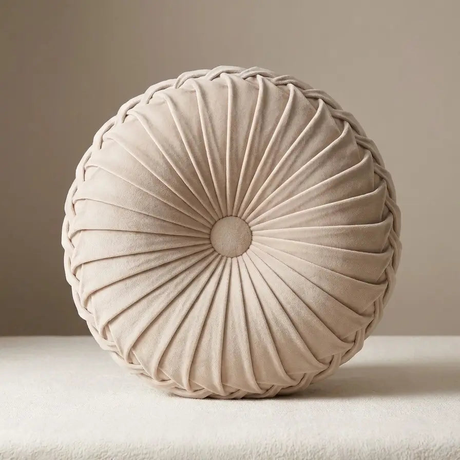 Coussin rond plissé en velours beige.