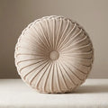 Coussin rond plissé en velours beige.