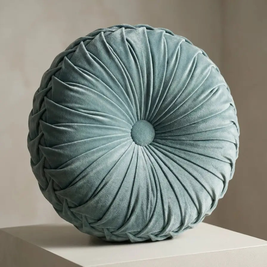 Coussin rond plissé en velours vert.