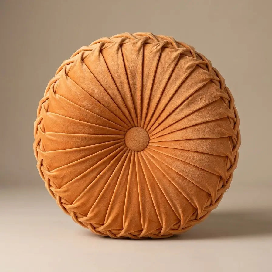 Coussin rond plissé en velours orange.